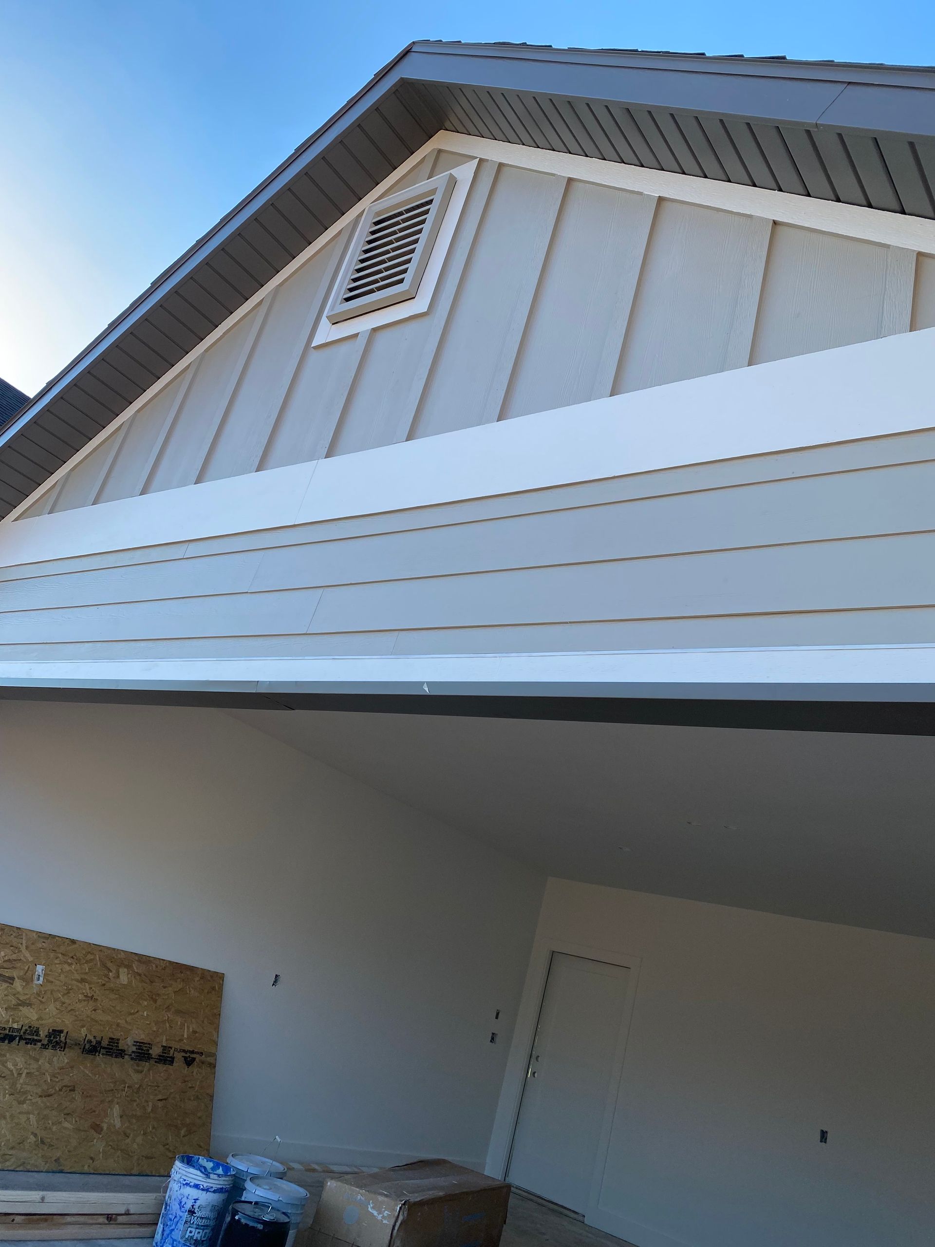 Exterior view of a house with light grey siding, white trim, and a dark roof.