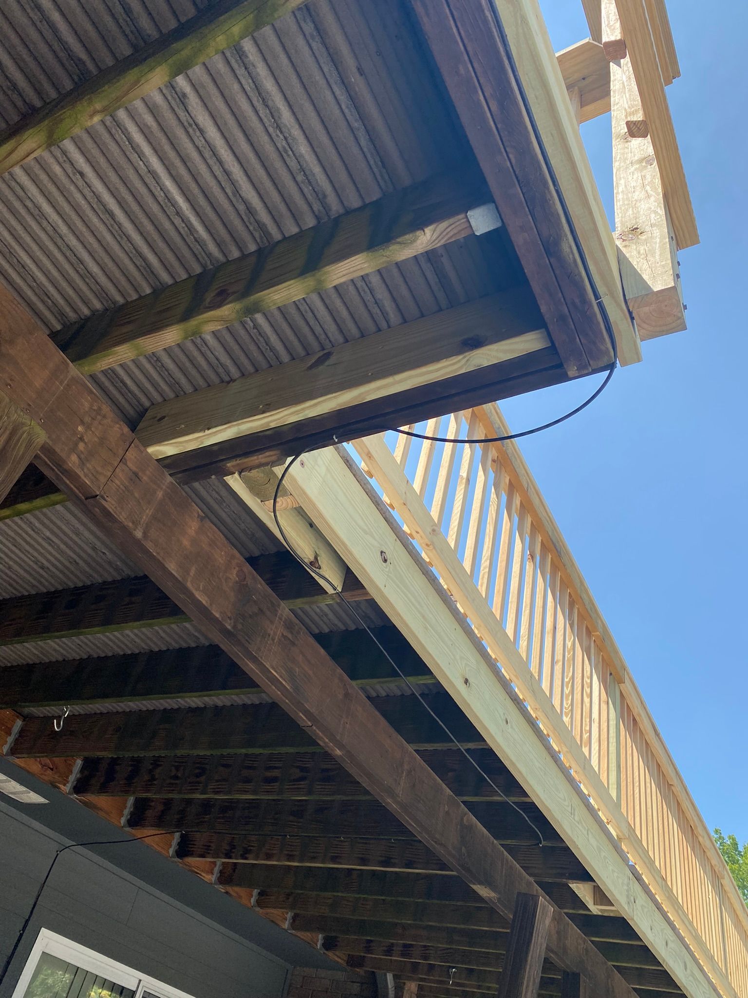 Wooden deck structure, various levels, support beams. Blue sky visible.