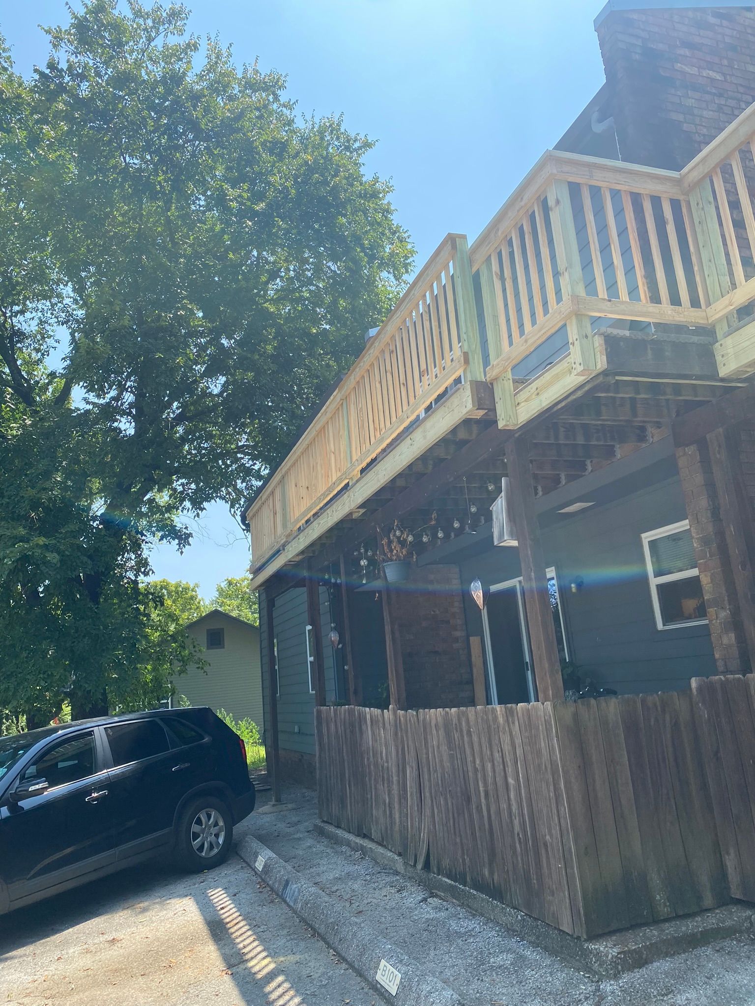Black SUV parked near a two-story building with a wooden deck.