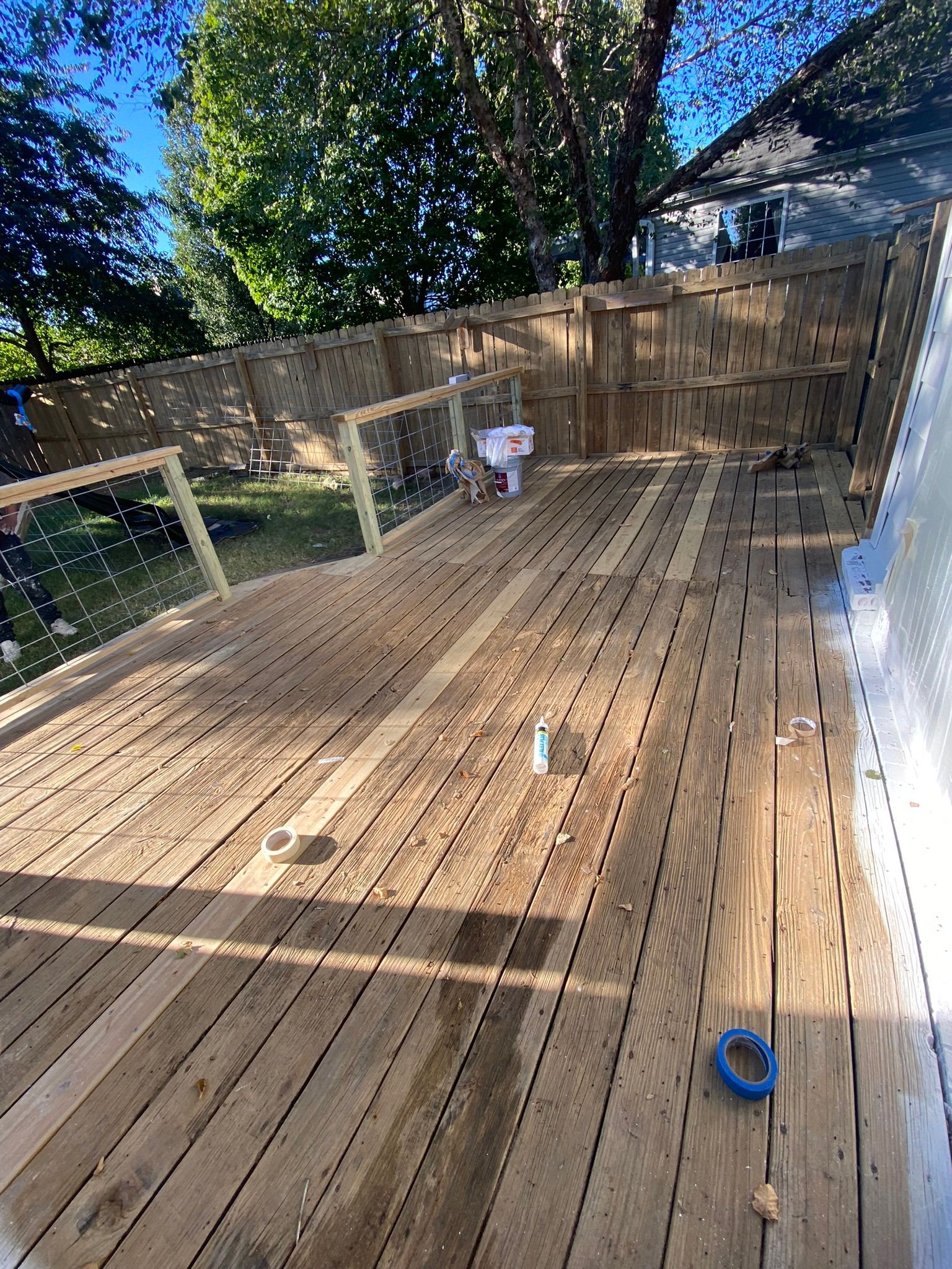 Wooden deck under construction with some railing and a partially visible house in the background.