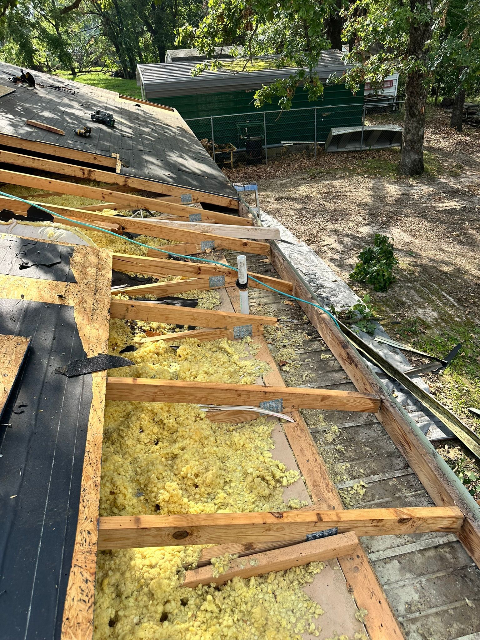 Rooftop undergoing renovation; wood framing, yellow insulation, and exposed sheathing are visible.