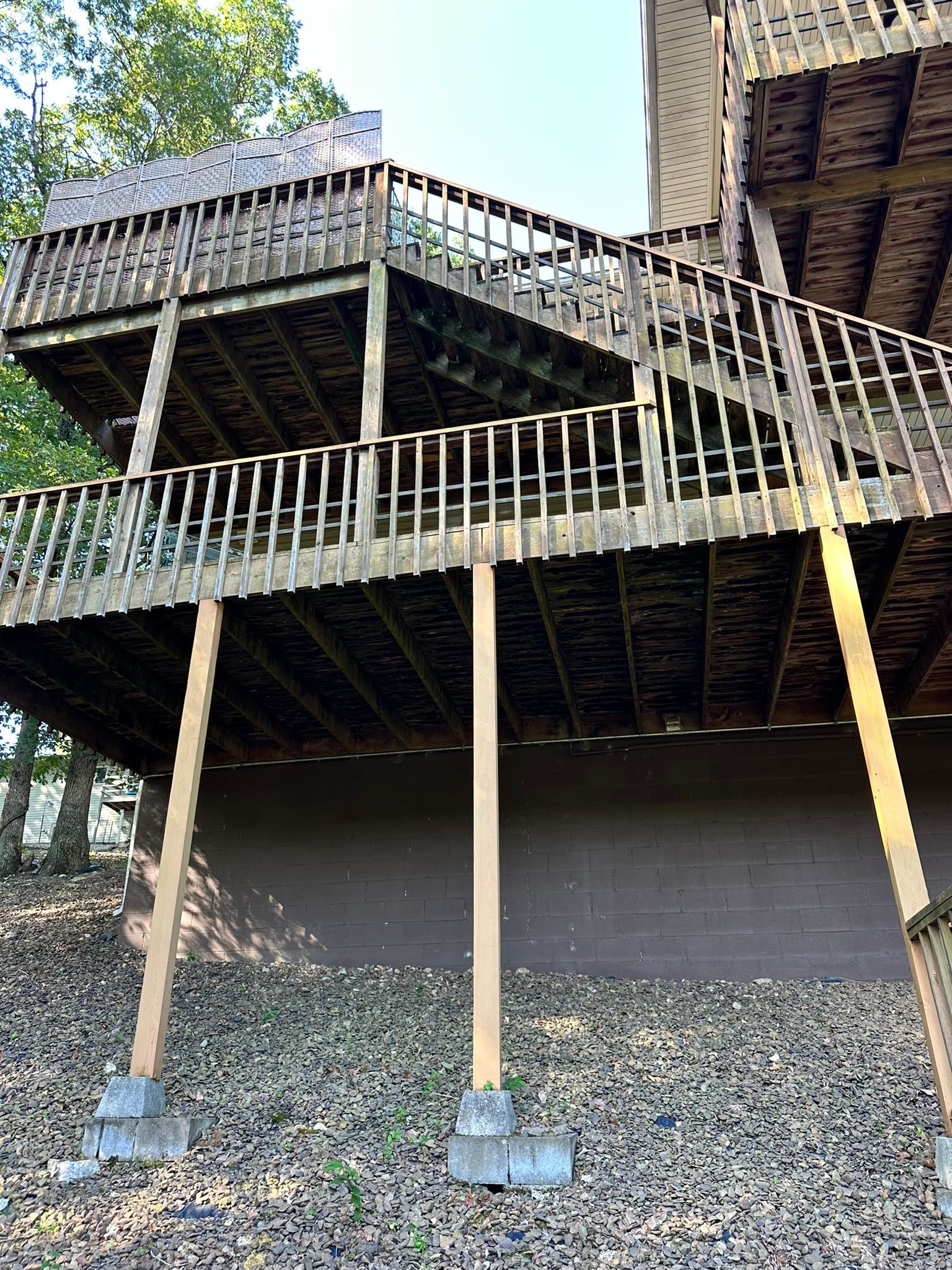 Multi-level wooden deck supported by posts, nestled amongst trees.