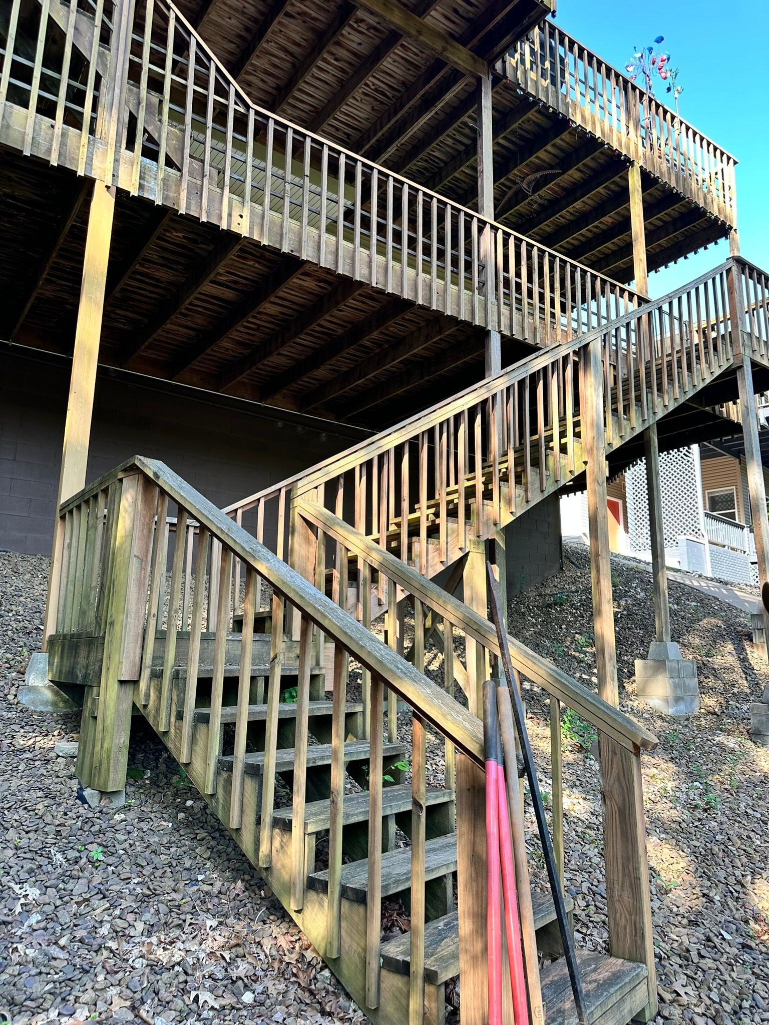 Wooden outdoor stairs lead up to multiple levels of a house with railings.