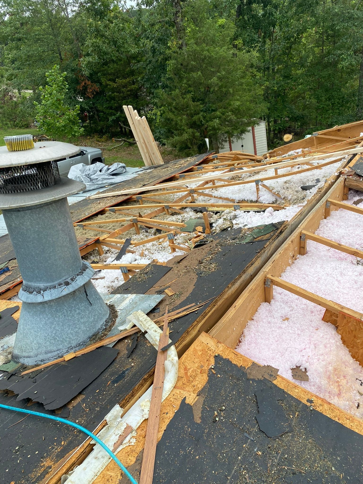 Roof partially dismantled; exposed wood framing, insulation, and chimney.