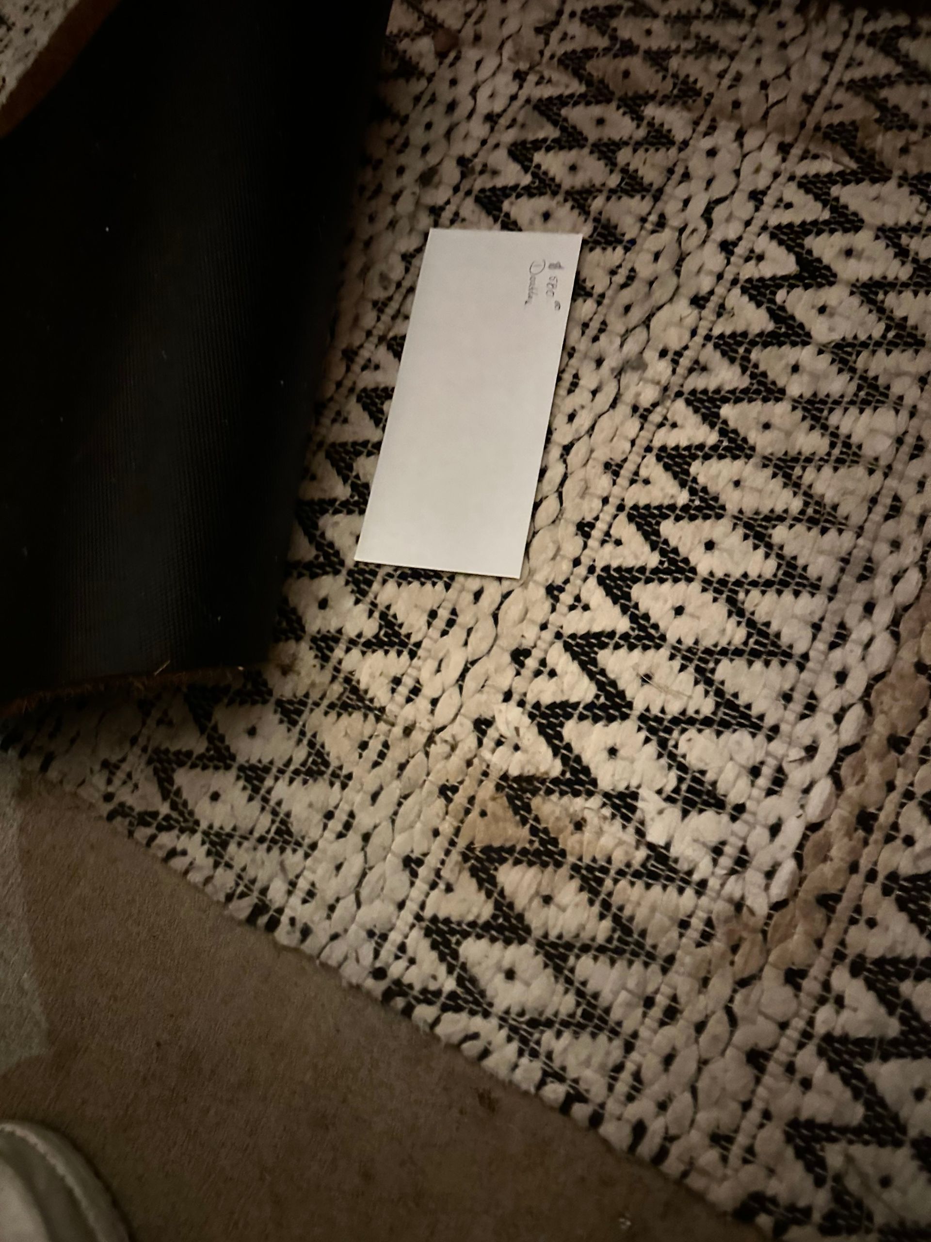 White paper on a patterned rug; black zig-zag design with beige background.