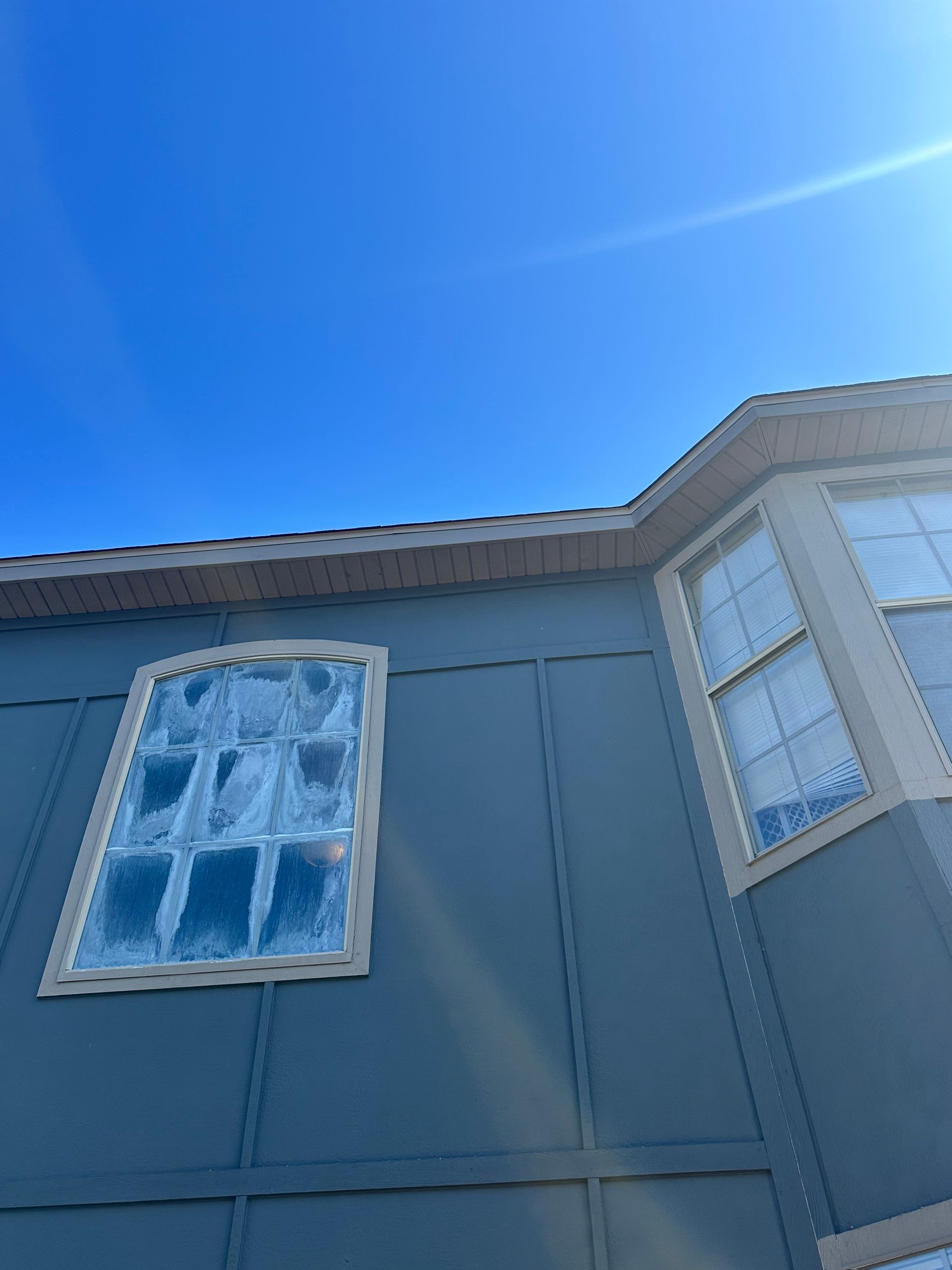 Blue house exterior with windows, blue siding, and clear sky.