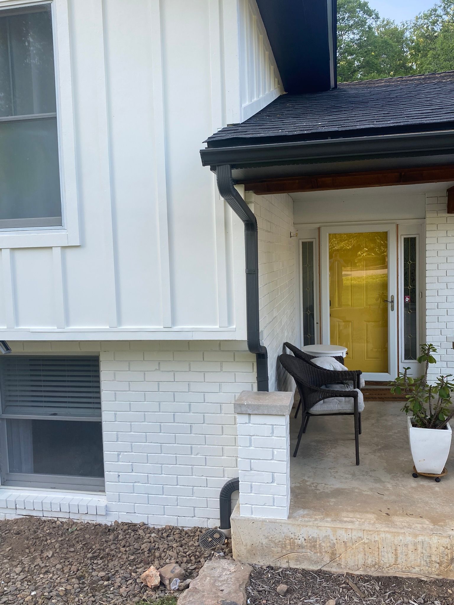 White house exterior with yellow door, black gutters, and white painted brick.