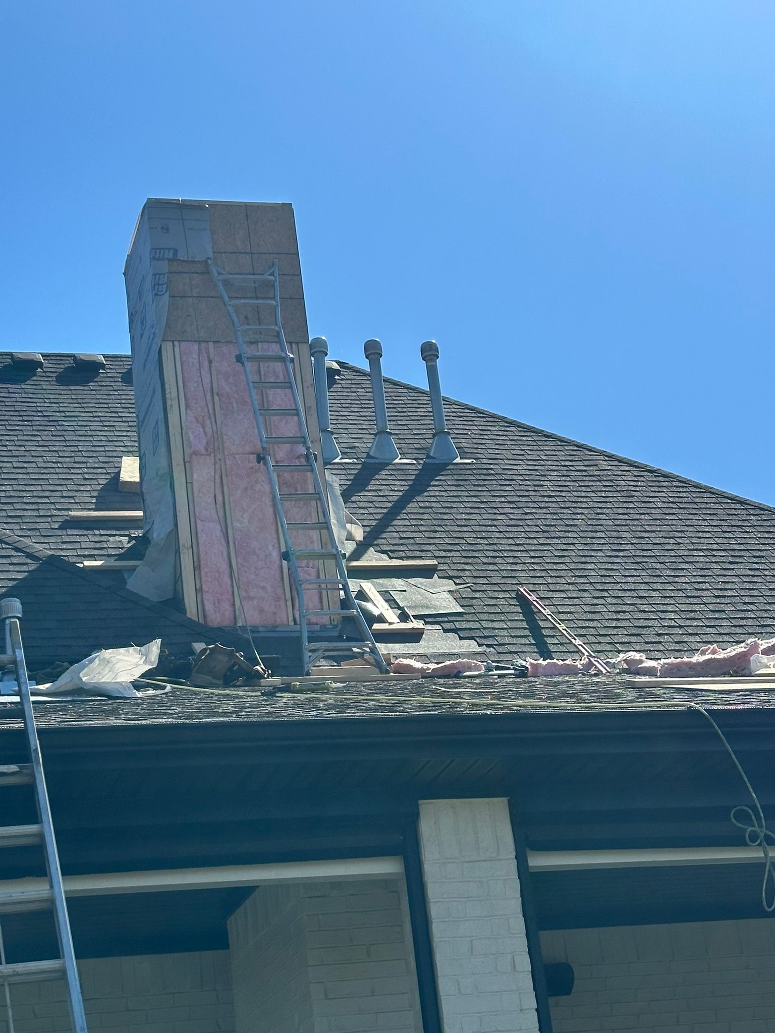 Chimney repair on a roof with visible damage, blue sky above.