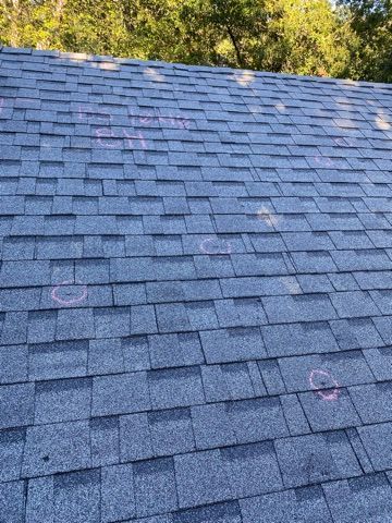 Dark gray asphalt shingle roof with pink circles marking potential damage.