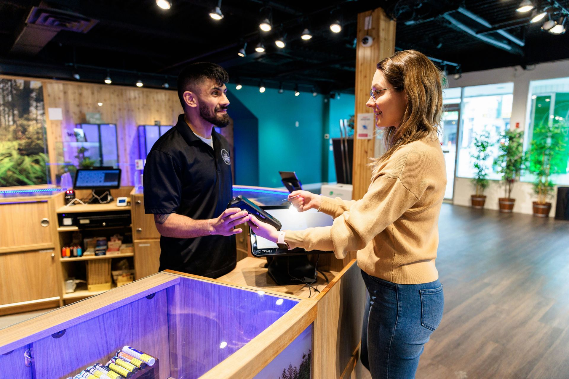 A woman is standing at a counter in a store talking to a man.