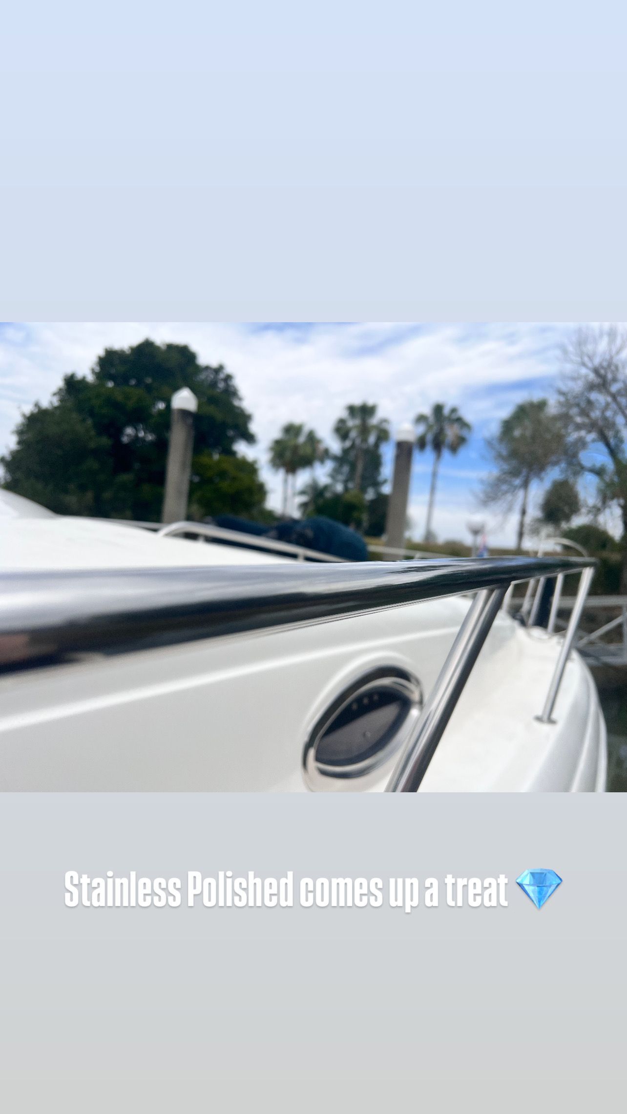 A close-up shot of a polished stainless steel boat railing, with the blurred outdoor marina background.