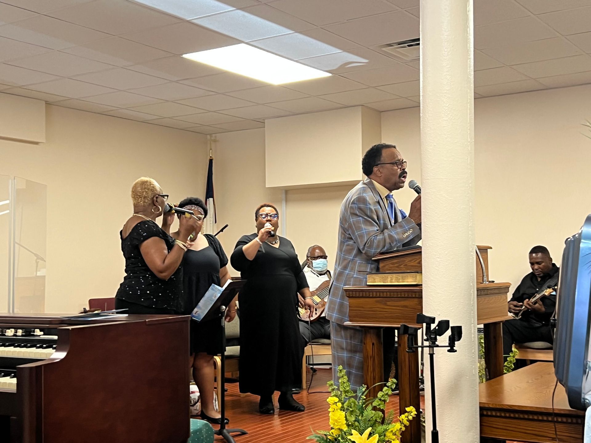 Choir singing and pastor speaking from the pulpit inside a church.