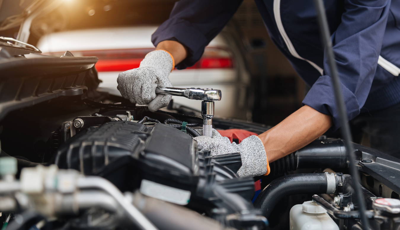 A mechanic is working on the engine of a car in a garage.