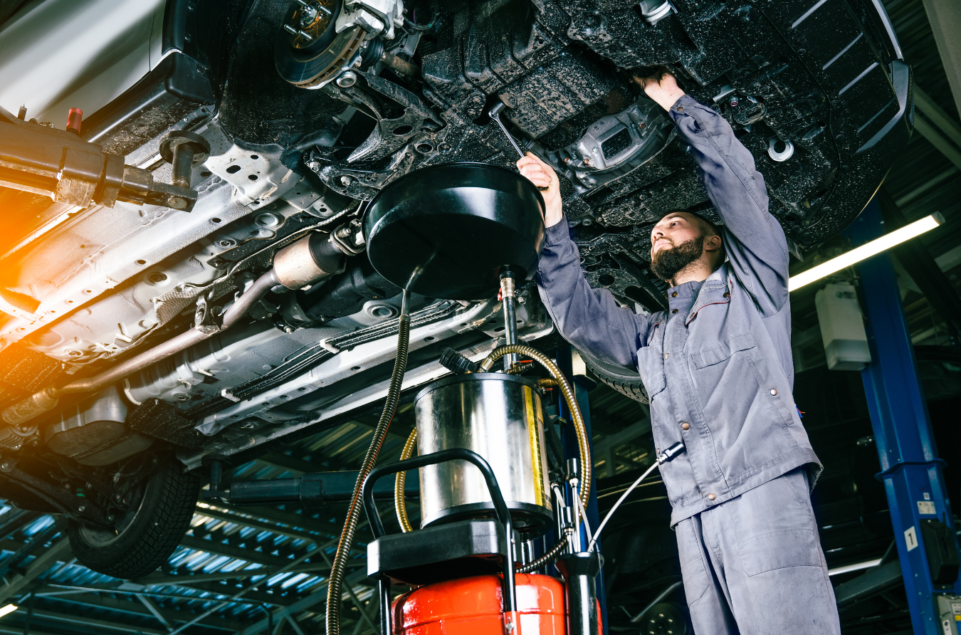 A man is working under a car in a garage.