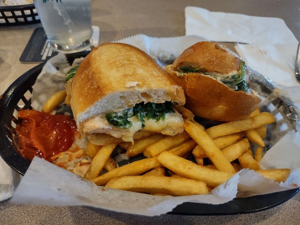 A sandwich and french fries in a basket on a table