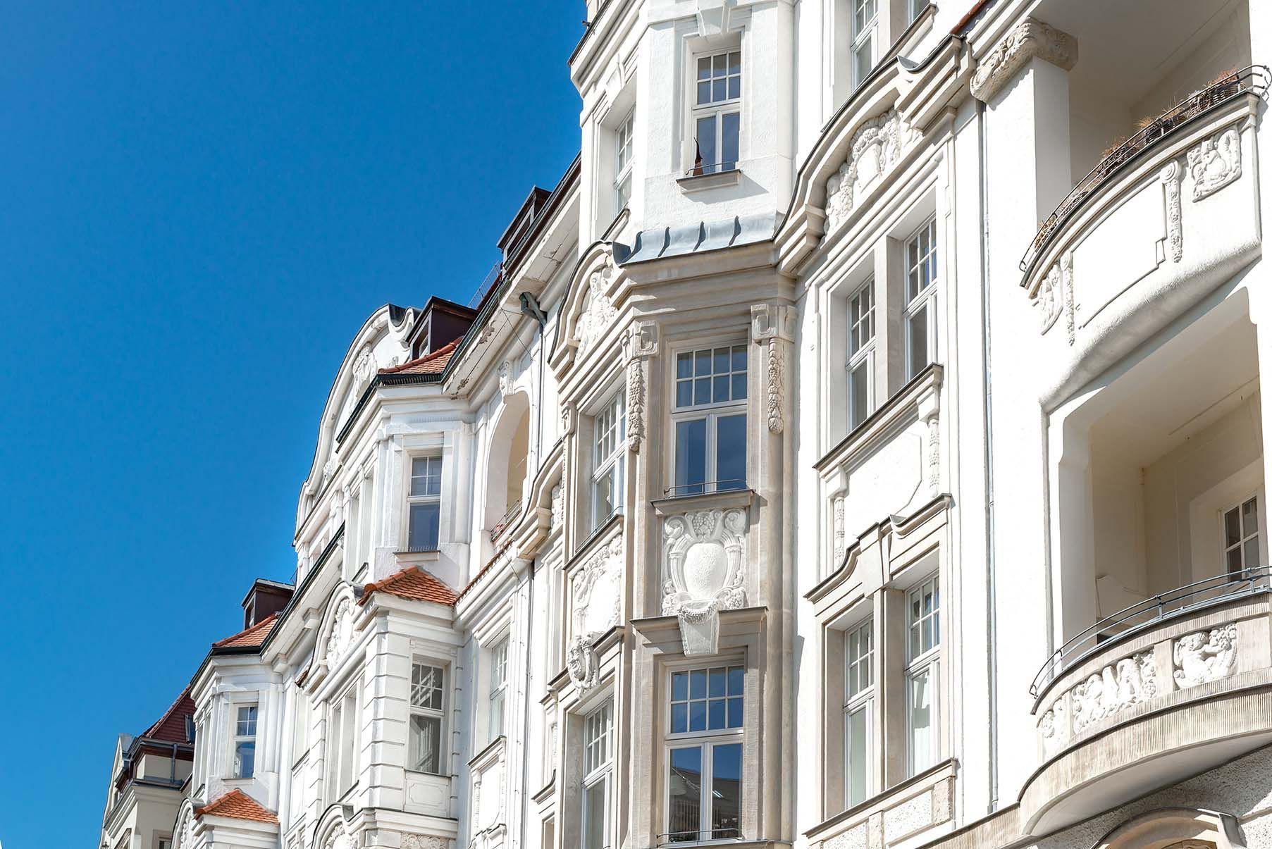 Eine Reihe weißer Gebäude mit Balkonen vor einem blauen Himmel.