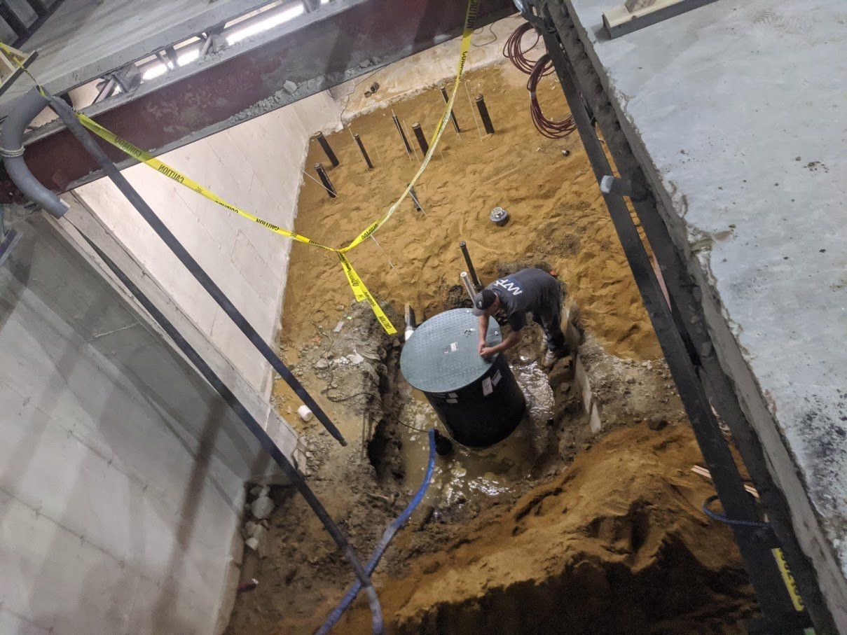 Man leaning on water container next to soil — Andover, MA — Merrimack Valley Plumbing