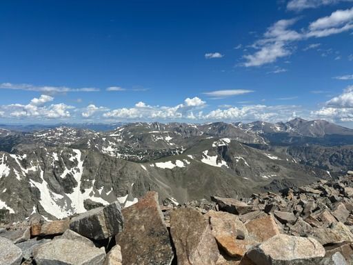 Mountain peaks under a blue sky, some with patches of snow.
