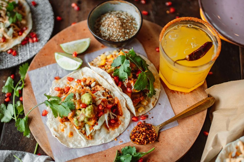 A wooden cutting board topped with tacos and a drink.