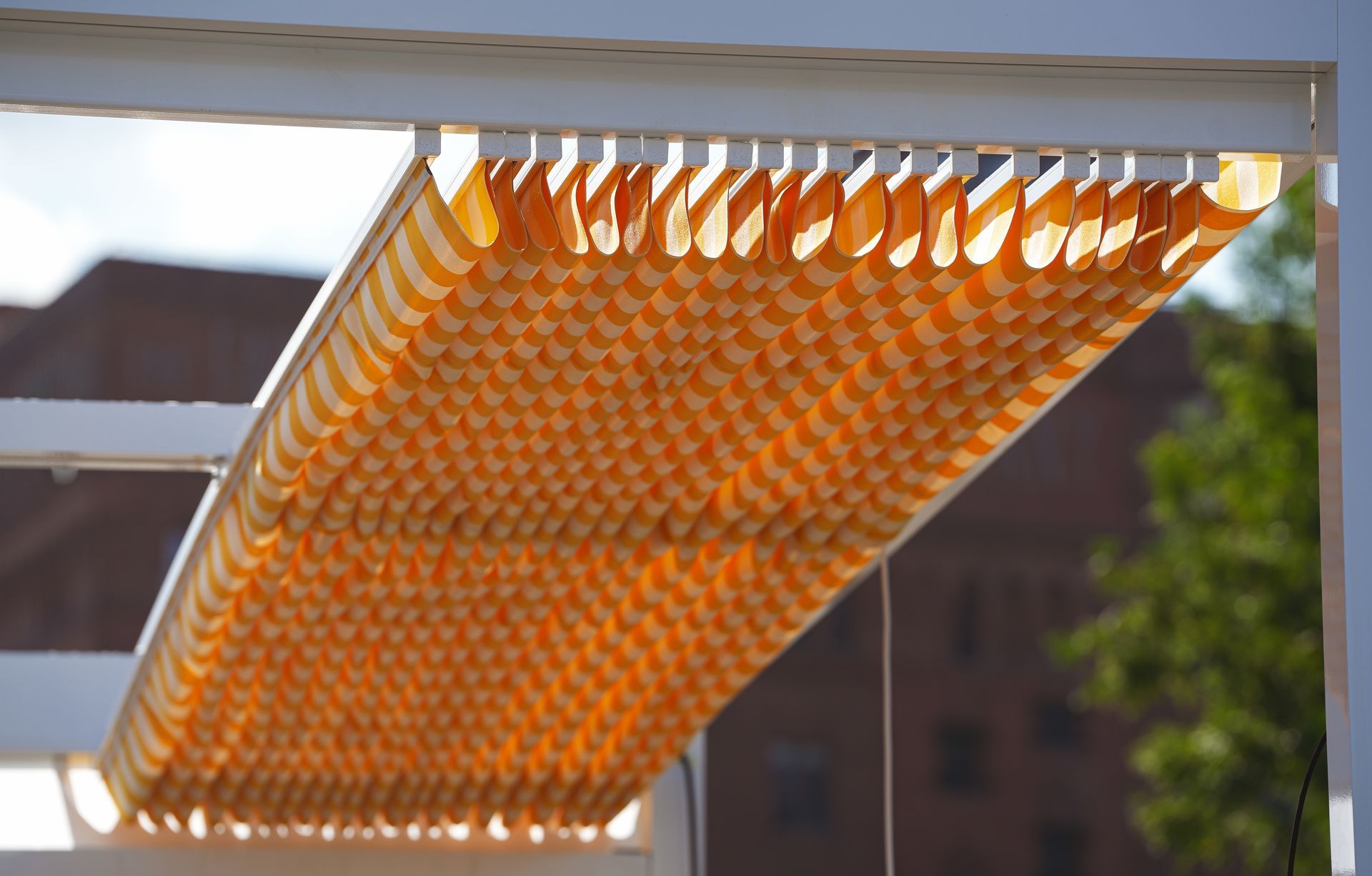 A yellow and white striped awning is hanging from a white frame
