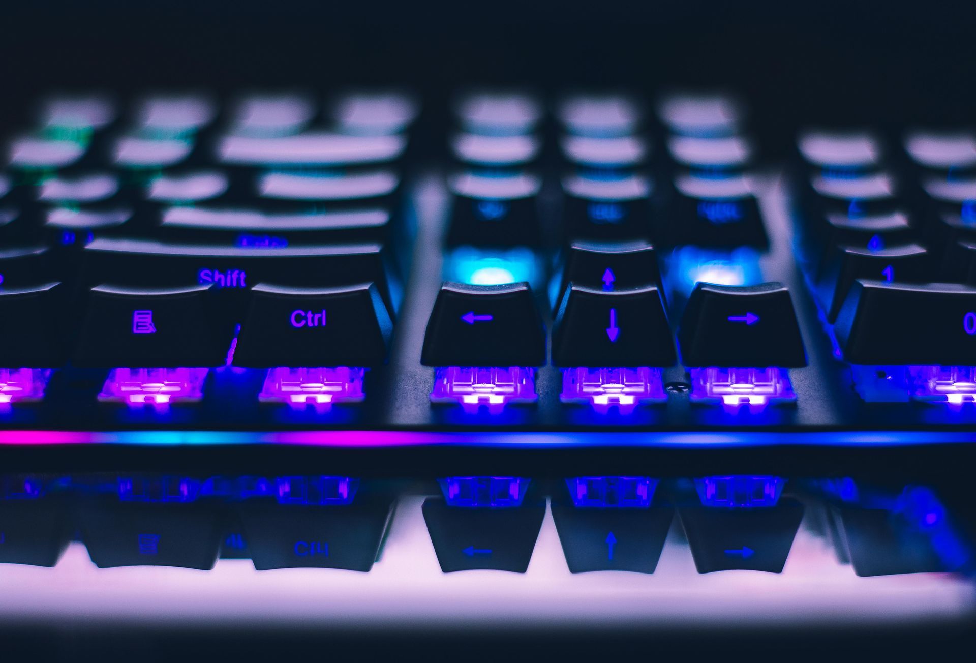 A close up of a keyboard with purple and blue lights on it.