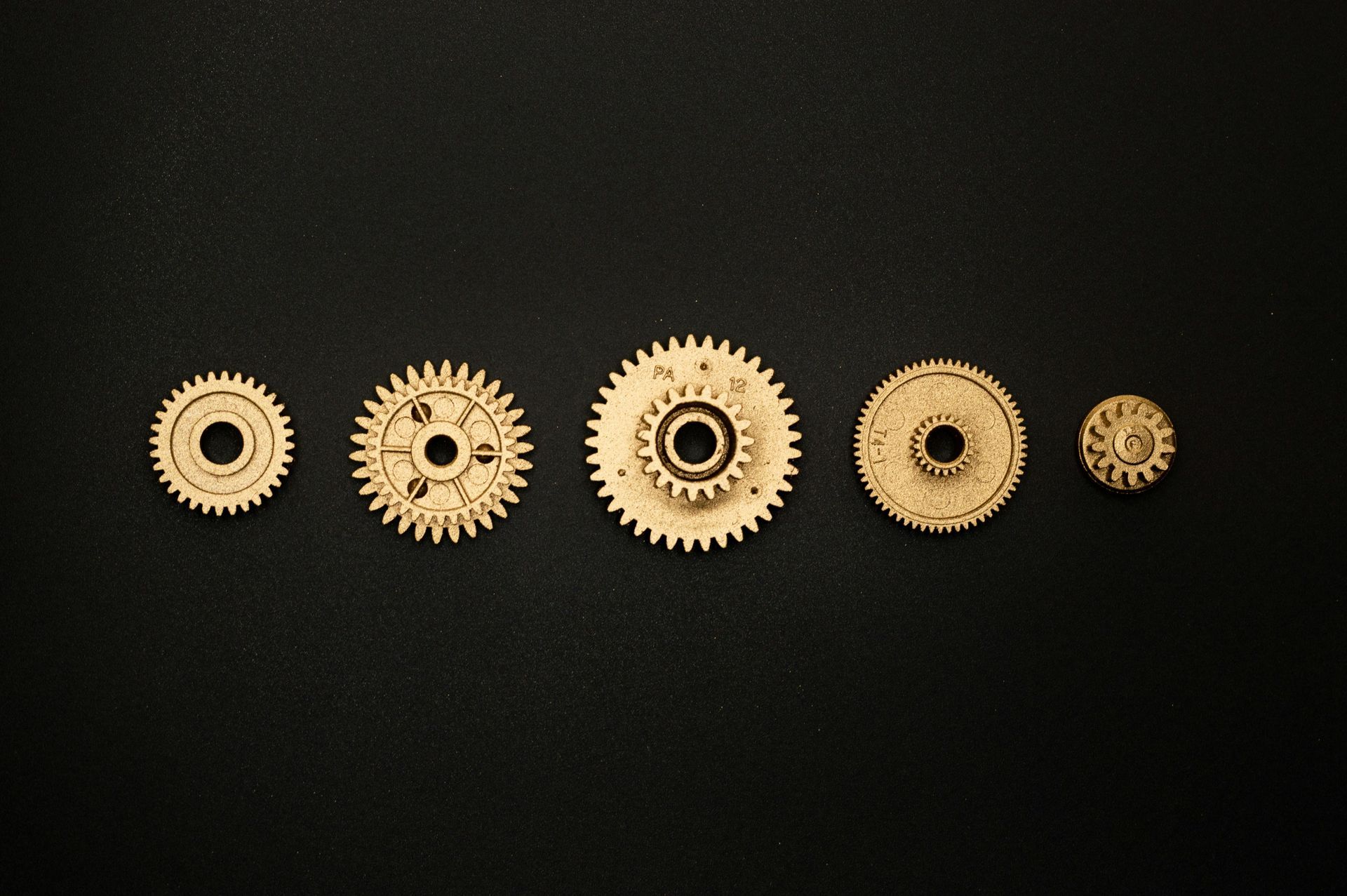 A group of gears are lined up on a black surface.