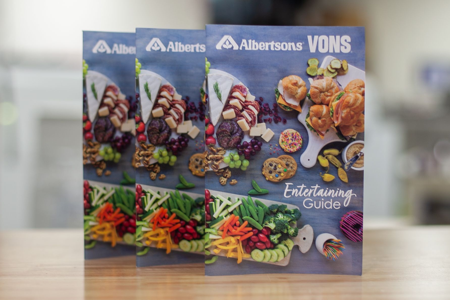 three albertsons vons entertaining guide books are sitting on a wooden table .