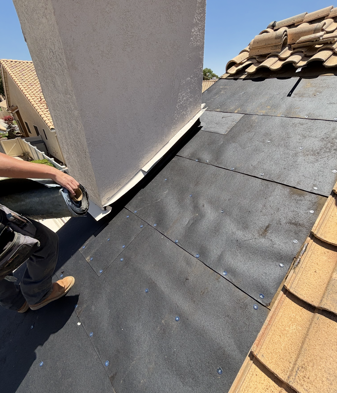 Roofer on flat roof installing material, with landscape area and mountains in background