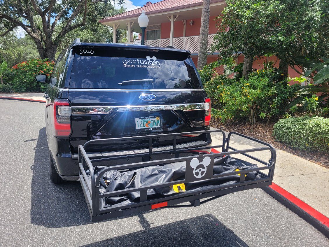 A white van is parked in the grass under a tree.