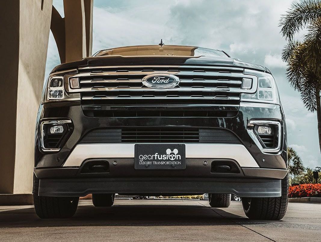 The front end of a ford expedition is parked in front of a building.