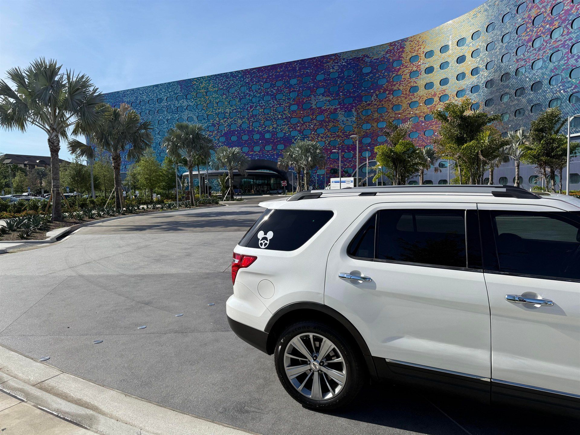 A white suv is parked in front of a colorful building.