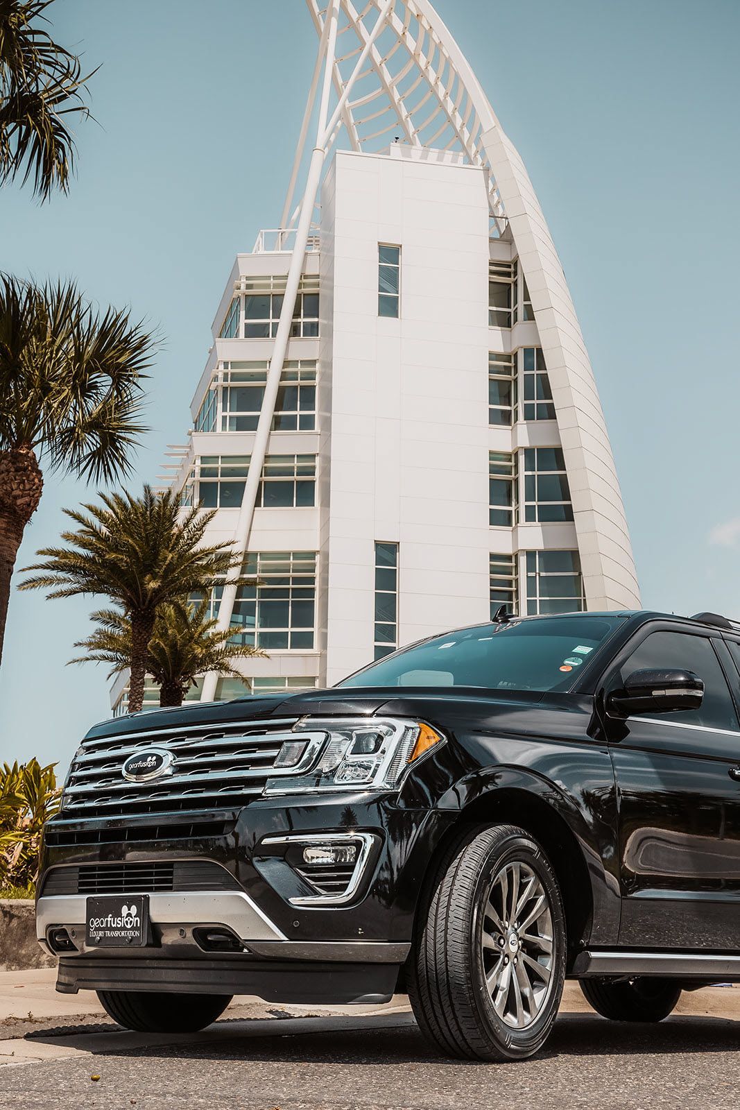 A black ford expedition is parked in front of a tall building.