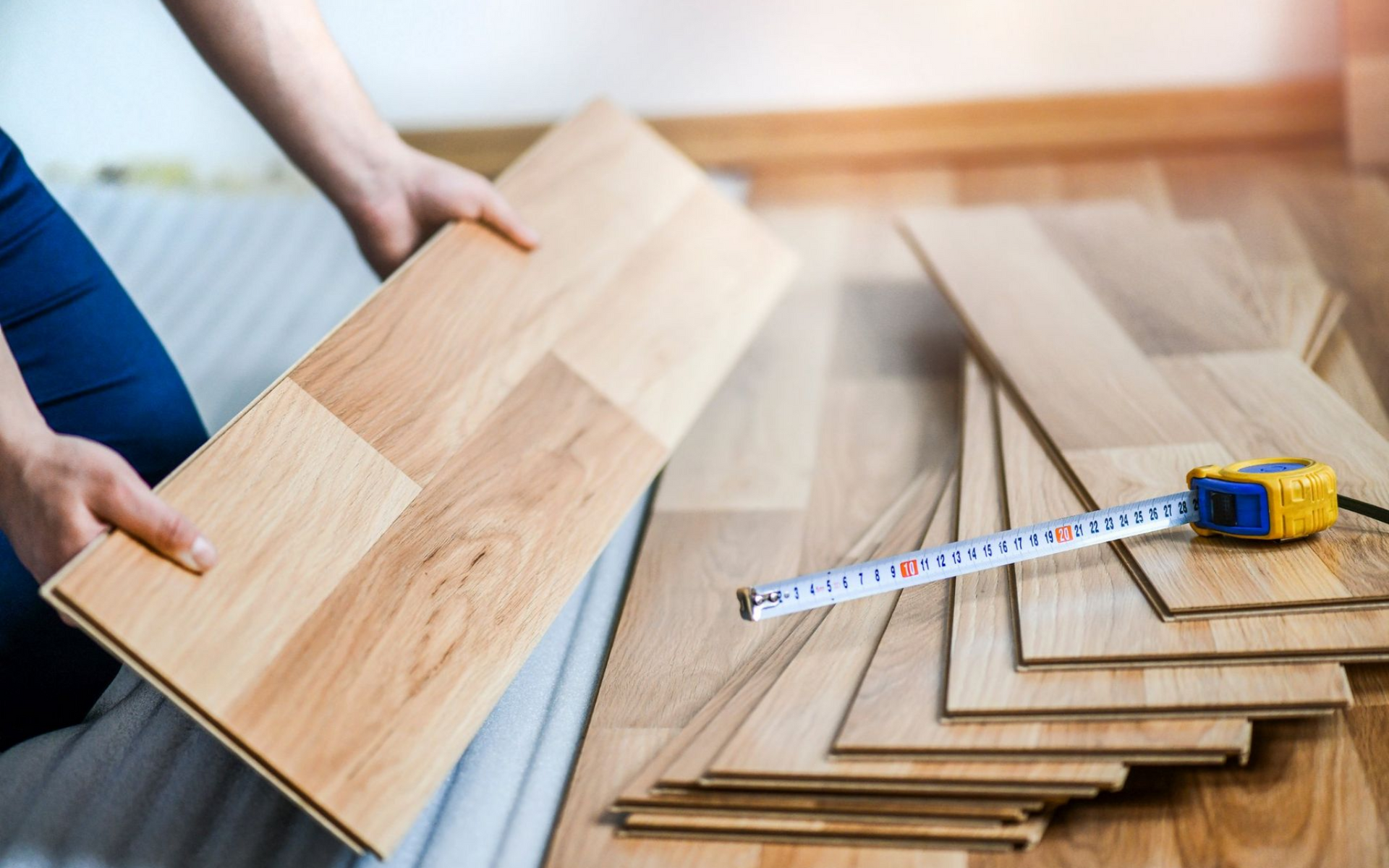 Person with magnifying glass inspecting a model house on a table.
