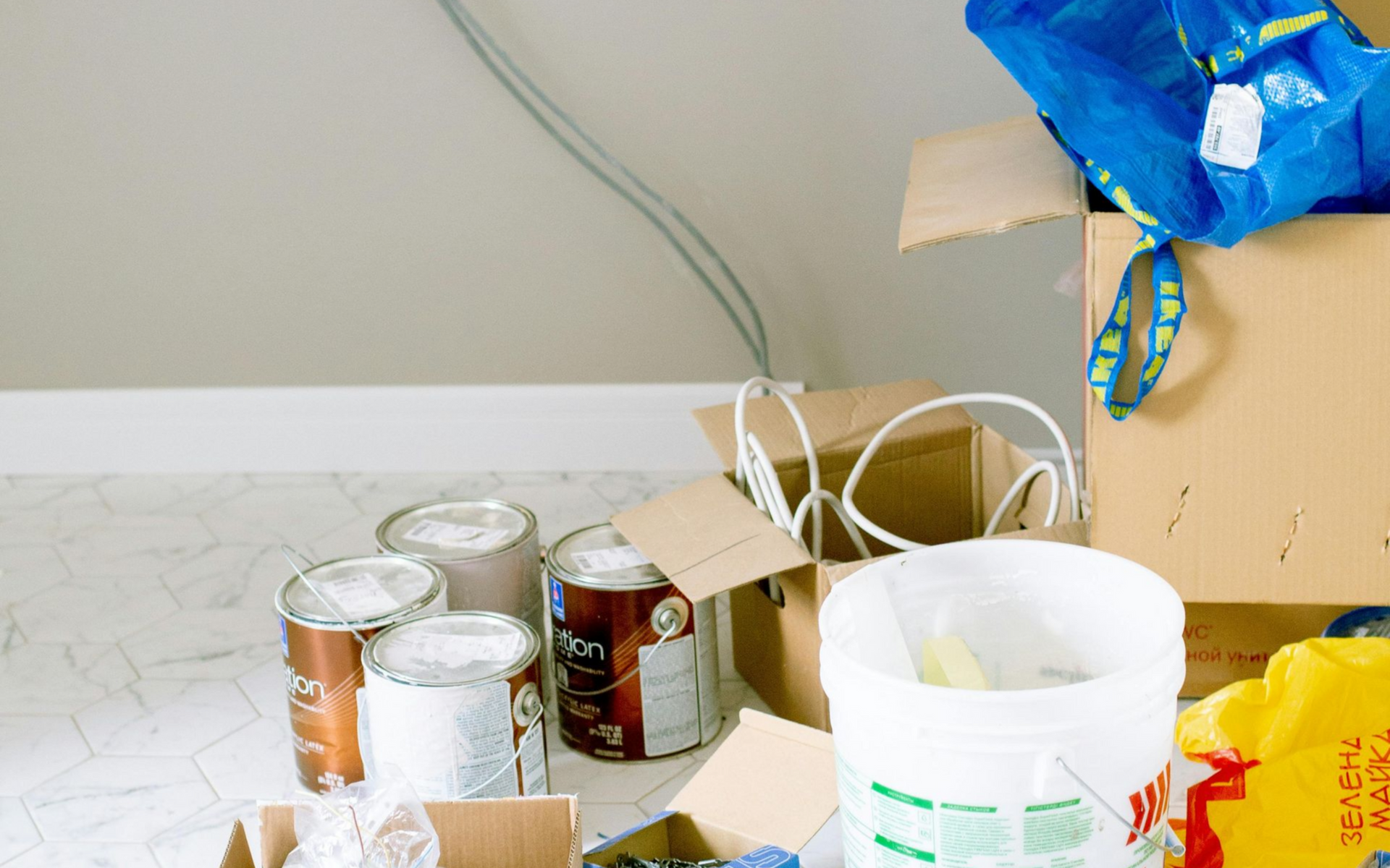 Interior of a house under construction; wooden studs frame walls and ceiling, with tools and materials scattered throughout.