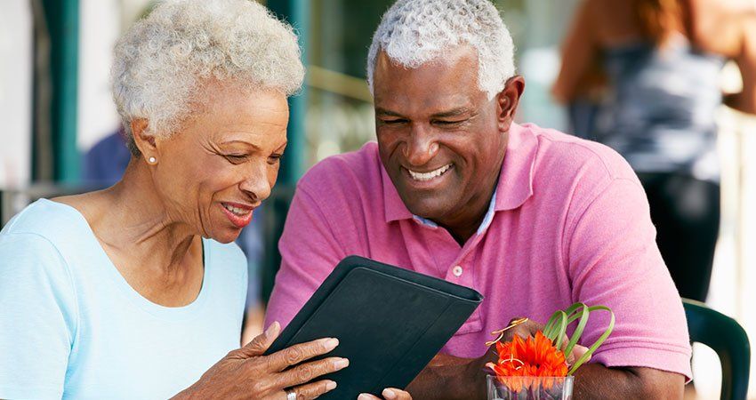 two older people look at tablet smiling