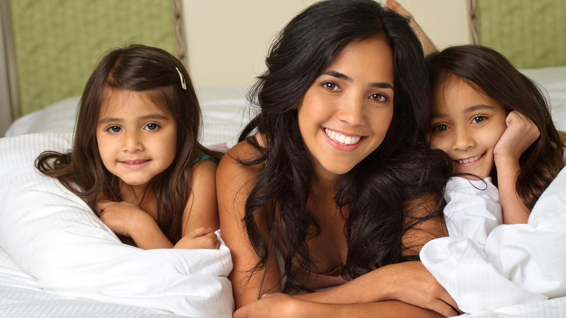 woman laying in a bed with two young children