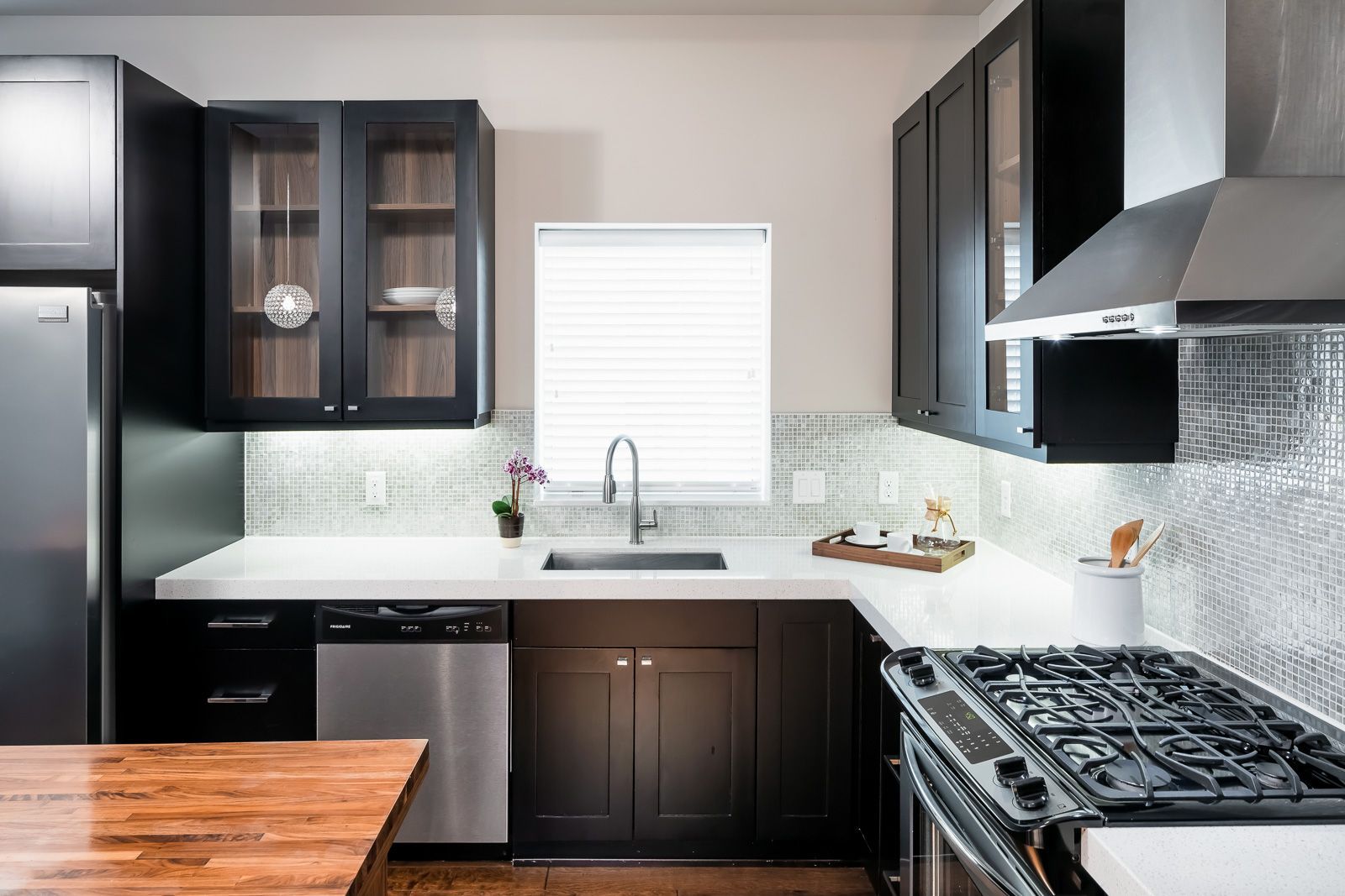 Modern kitchen with dark cabinets, stainless appliances, and a window above the sink.