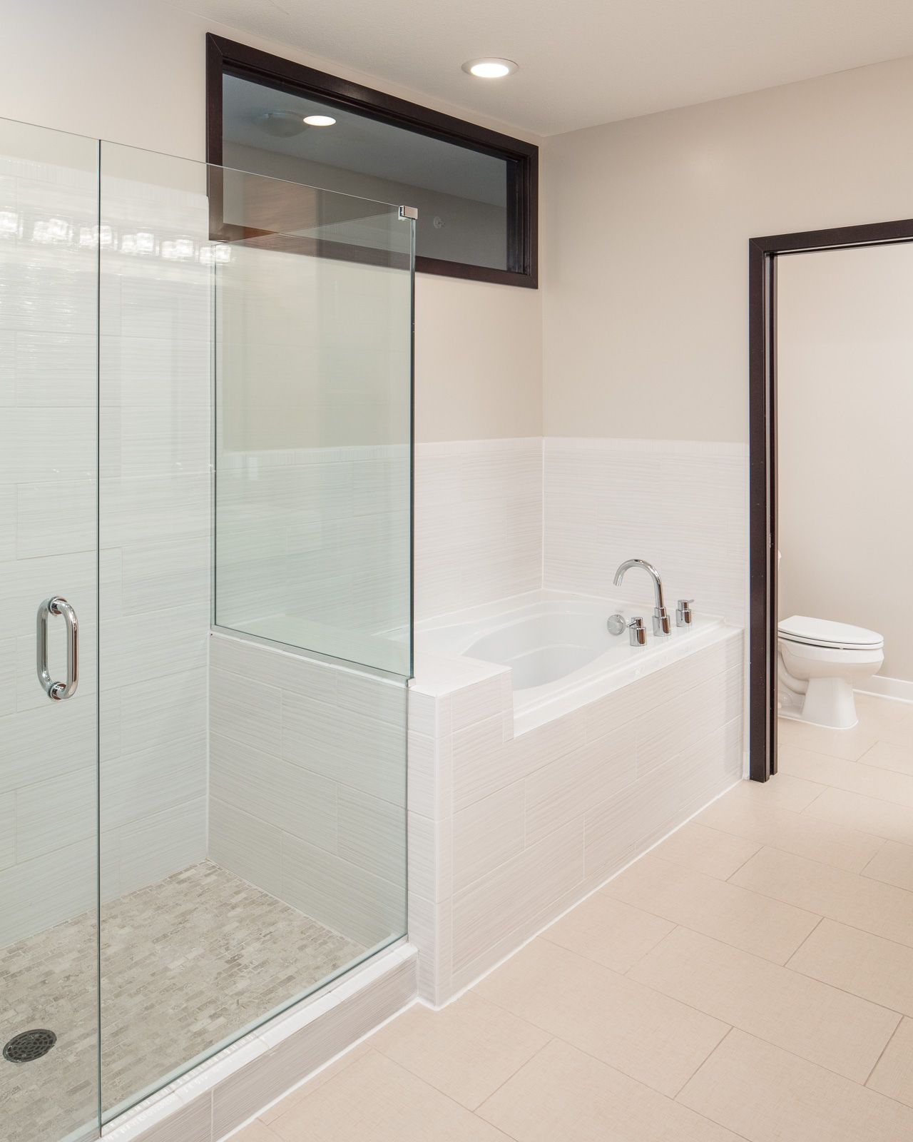 Modern apartment bathroom with glass shower enclosure, built-in tub, and adjacent toilet.
