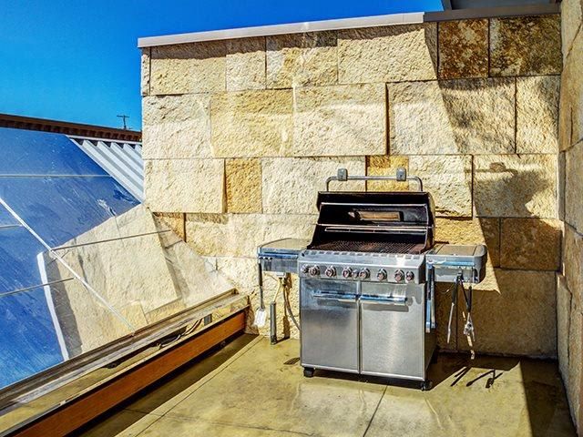 Outdoor grilling station on a stone-walled rooftop patio.