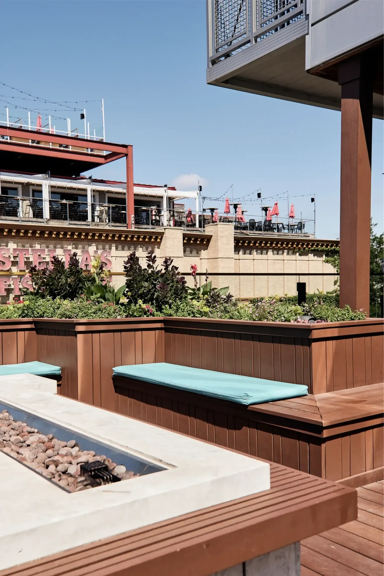 Rooftop outdoor lounge with wooden benches, planters, and a fire pit.