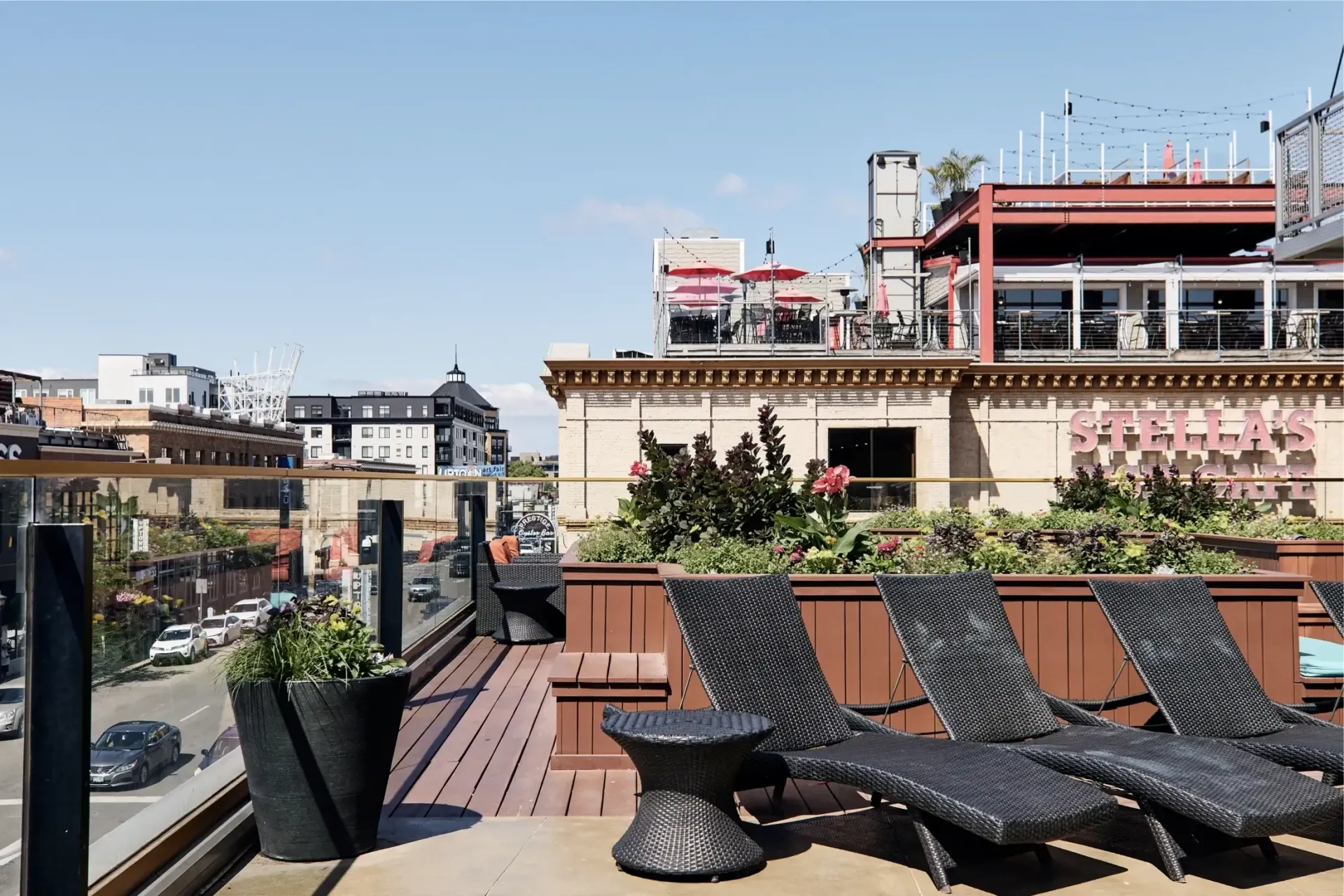 Rooftop terrace with lounge chairs, planters, and city skyline.