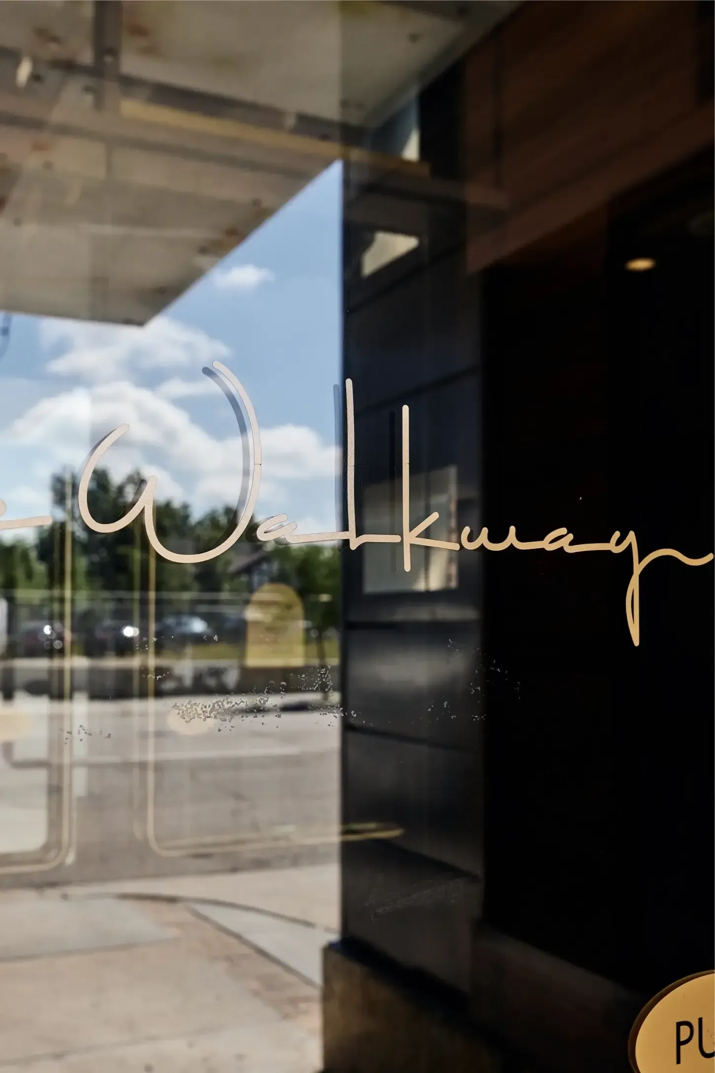 Glass entrance door with cursive sign, reflecting street outside.