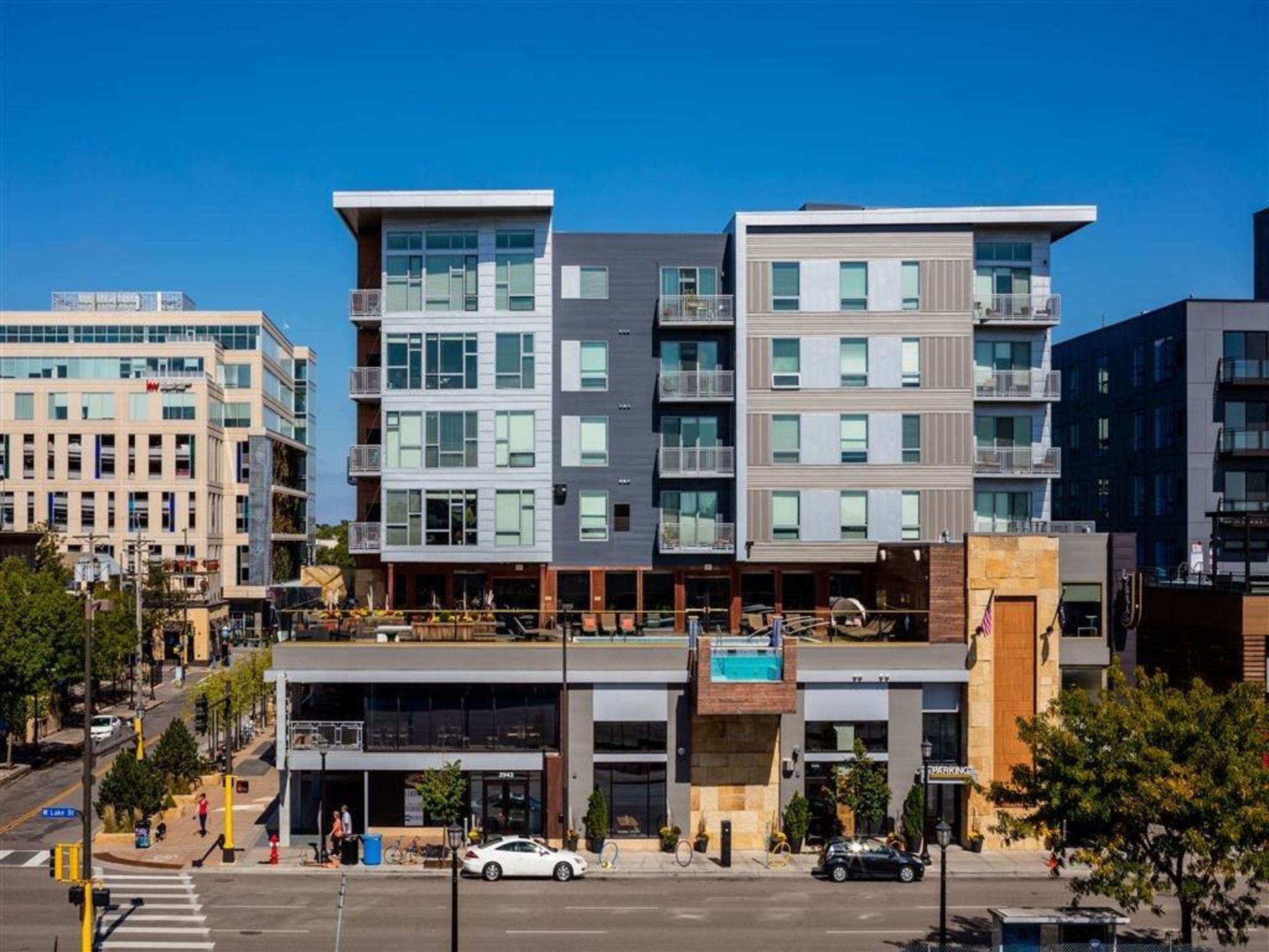 Exterior view of a modern multi-story apartment building with balconies along a city street.