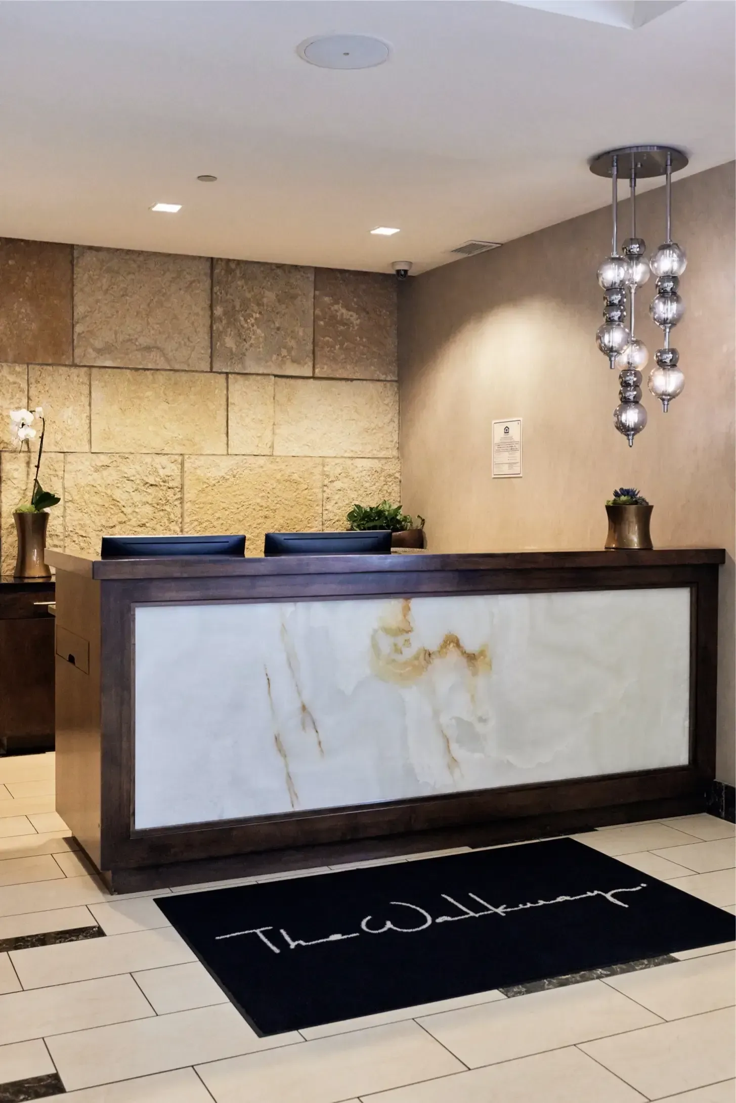 Lobby reception desk with a marble panel, stone wall, and hanging pendant lights.