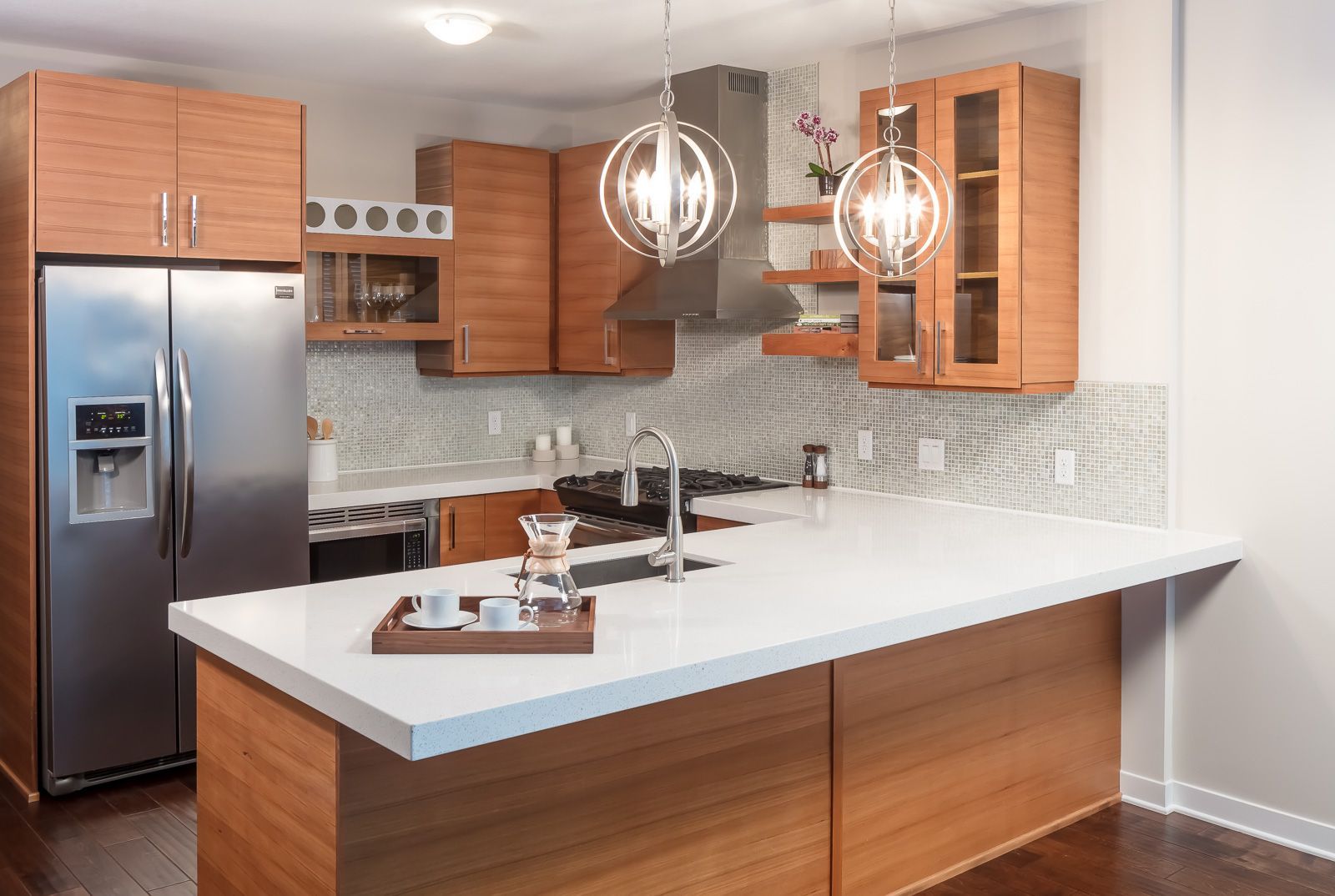 Modern kitchen with an island, wooden cabinets, stainless steel appliances, and pendant lights.