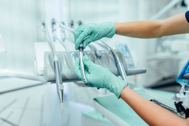 A dentist is holding dental instruments in her hands in a dental office.