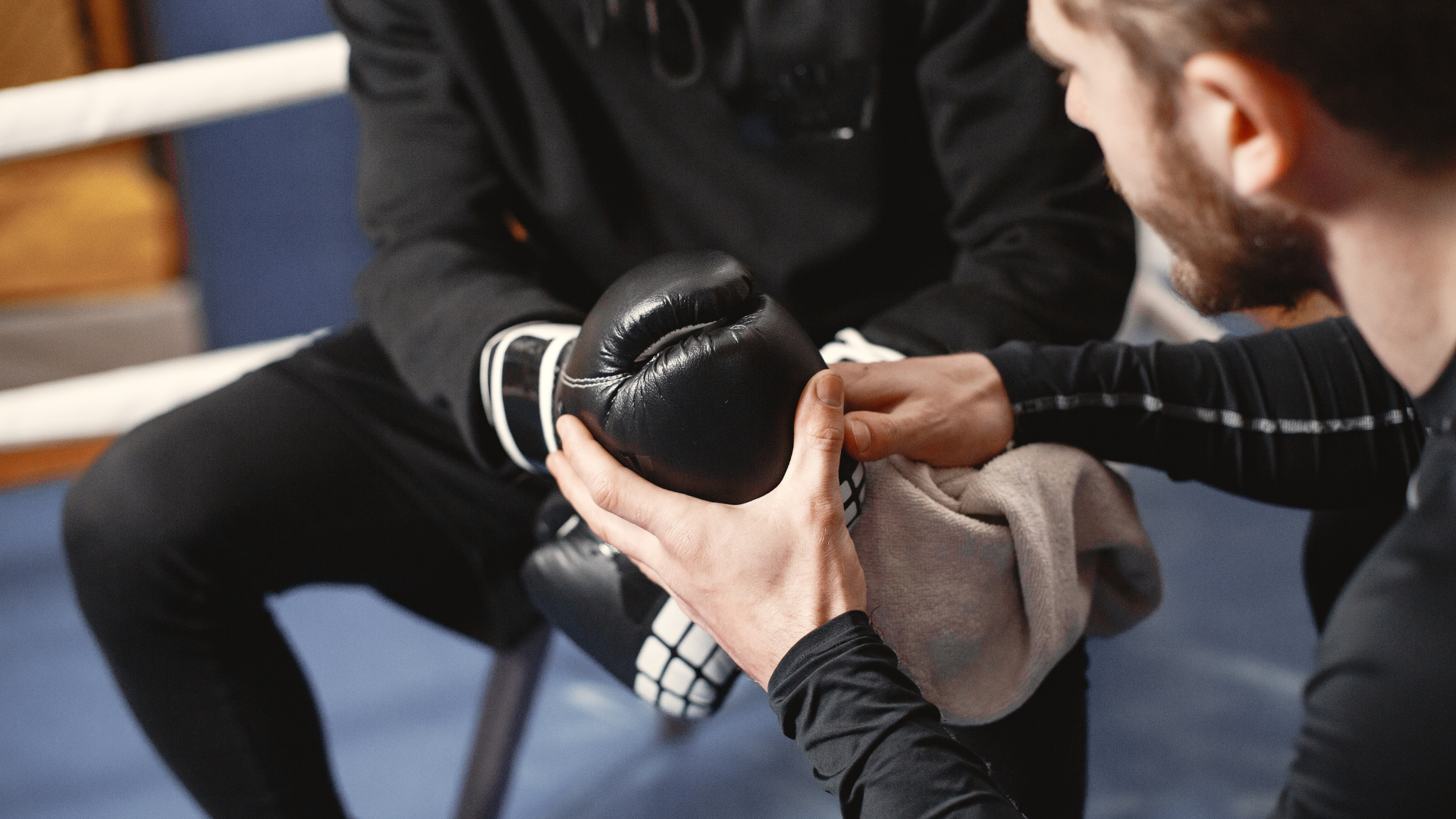 A man is cleaning his boxing gloves with a towel.