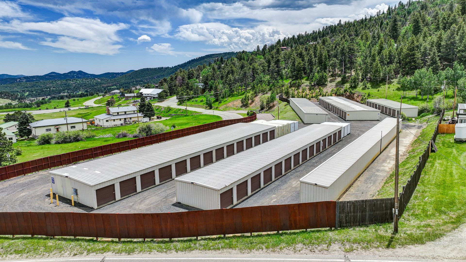 Storage units nestled among trees in a green, mountainous setting.