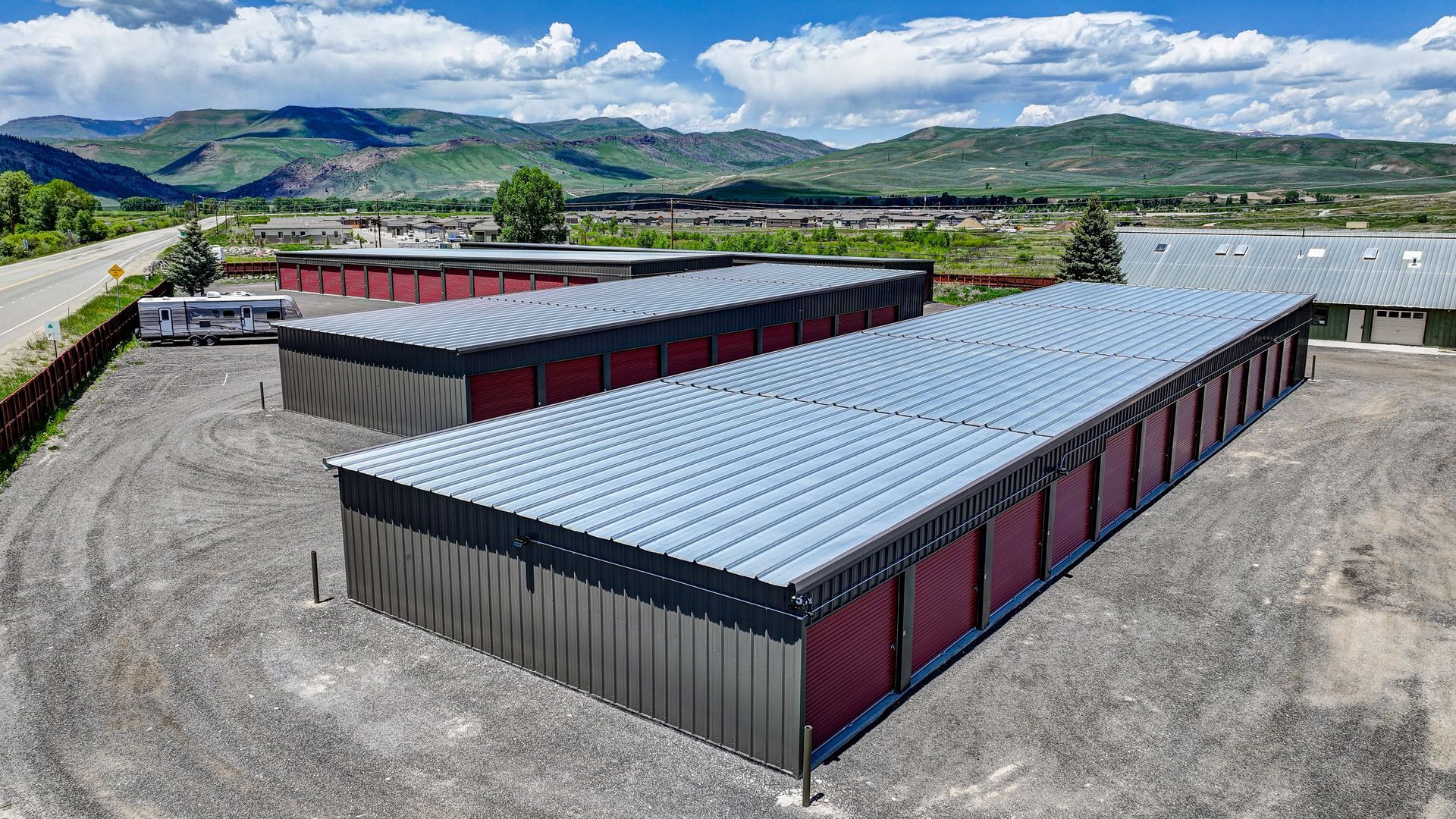 Storage units nestled among trees in a green, mountainous setting.