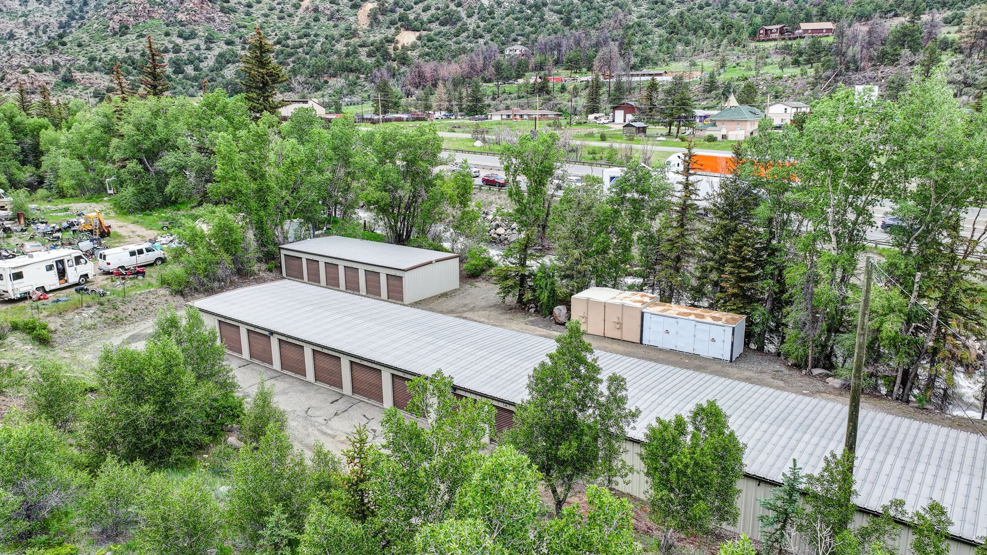 Storage units nestled among trees in a green, mountainous setting.